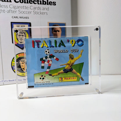 A clear acrylic case displaying a Panini sticker pack with an illustration of a soccer player in action.